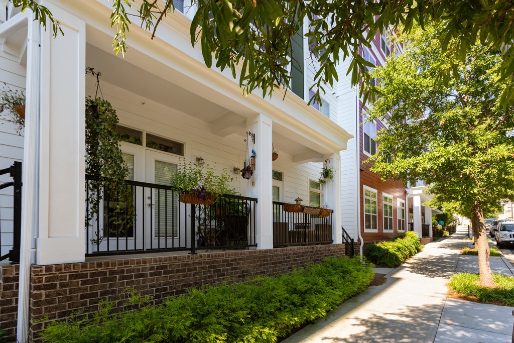 A white building with a balcony and plants hanging from it.