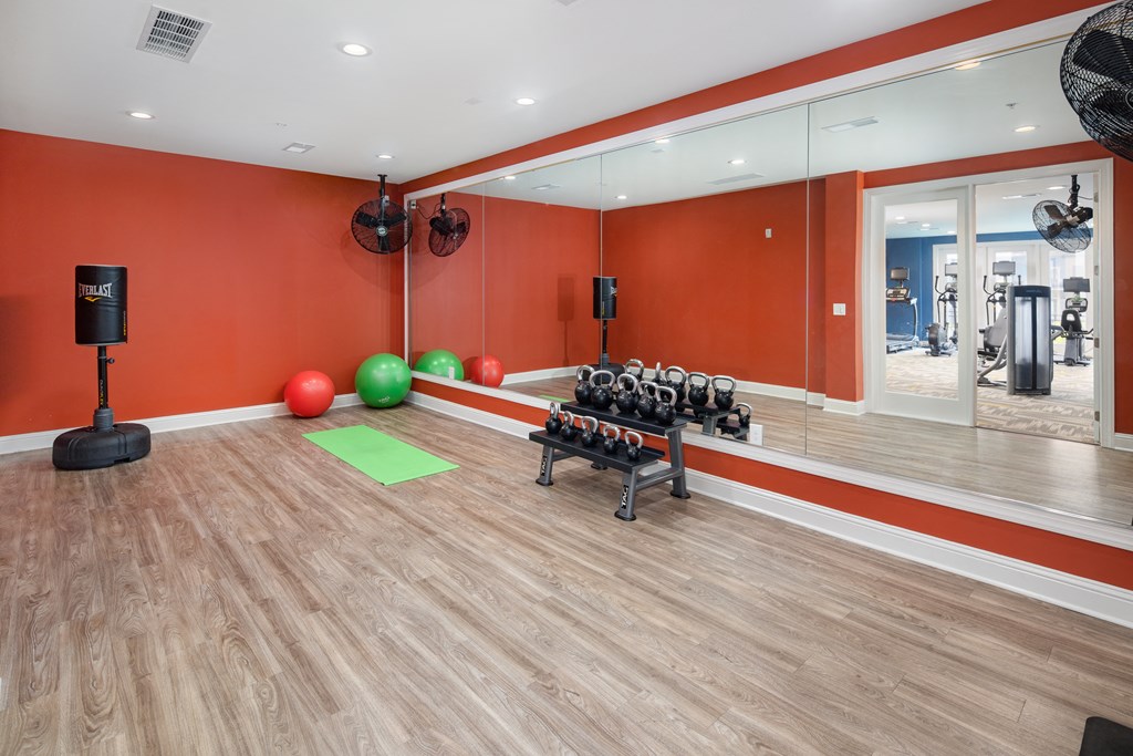 A gym with orange walls and wooden floors.