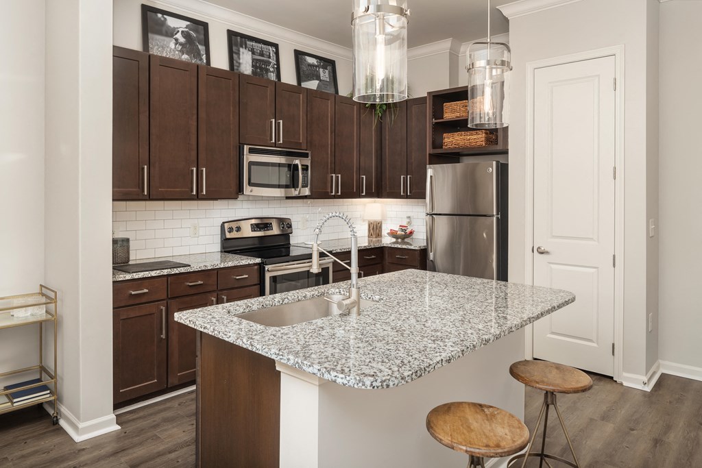 A kitchen with a granite countertop and wooden stools.