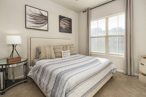 A bedroom with a bed, nightstand, and two framed pictures on the wall.