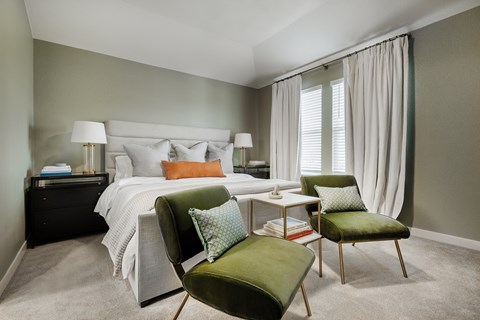 A bedroom with a bed, nightstand, chair, and window.