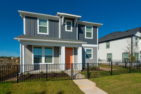 A modern house with a grey and white exterior and an orange door.