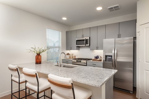 A kitchen with a granite countertop and stainless steel appliances.