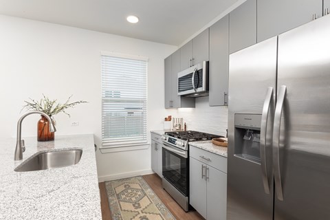 A kitchen with a stainless steel refrigerator, oven, and sink.