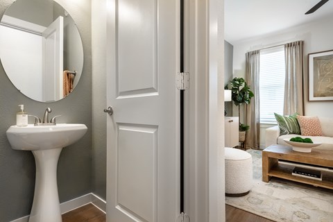 A bathroom with a white pedestal sink and a mirror.