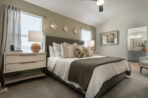 A bedroom with a large bed and a nightstand with a lamp.