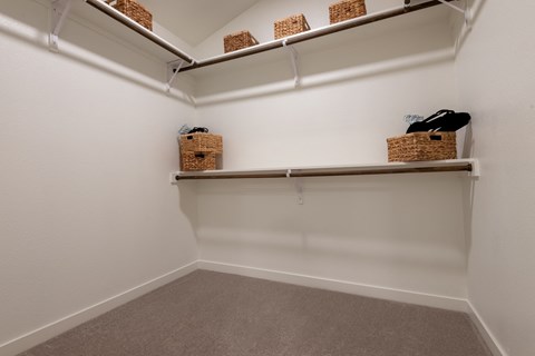 A white closet with three shelves and two baskets on the bottom shelf.