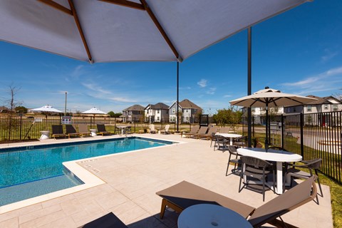 A pool area with a table and chairs under a canopy.