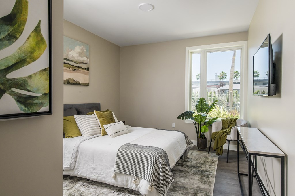 a bedroom with a bed and a desk and a window