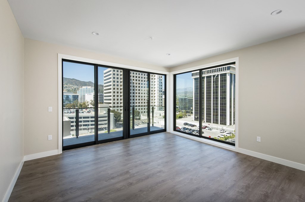 an empty living room with large windows and a city view