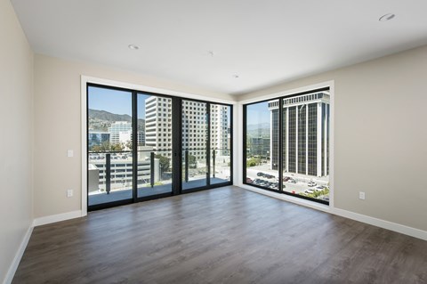 an empty living room with large windows and a city view