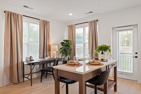 A dining room with a table set for two and a potted plant on the table.