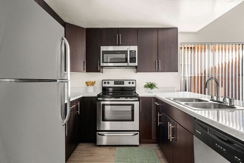 A modern kitchen with dark brown cabinets and stainless steel appliances.