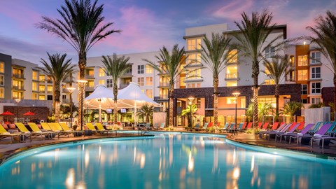 A large swimming pool in front of a building with palm trees.