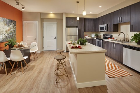A kitchen with a white island and a dining table with chairs.