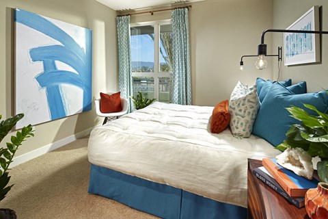 A bedroom with a large bed and a blue and white abstract painting on the wall.