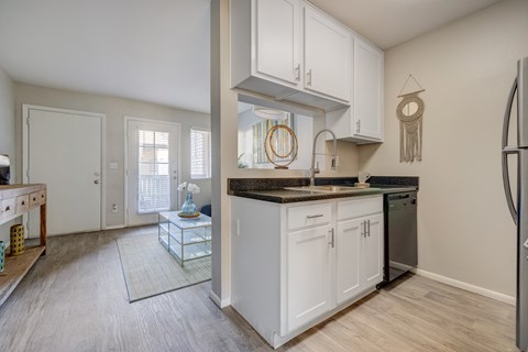A kitchen with white cabinets and a black fridge.