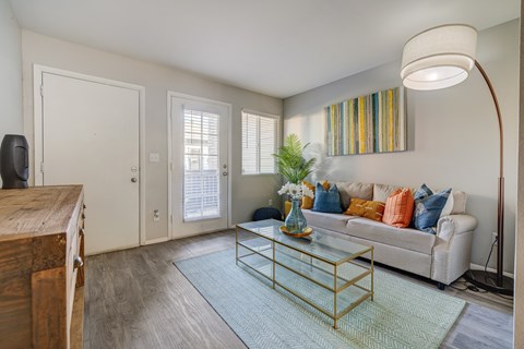 A living room with a white couch and a glass coffee table.