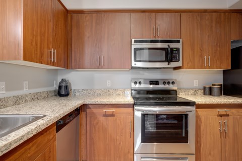 A kitchen with wooden cabinets and a stainless steel oven.