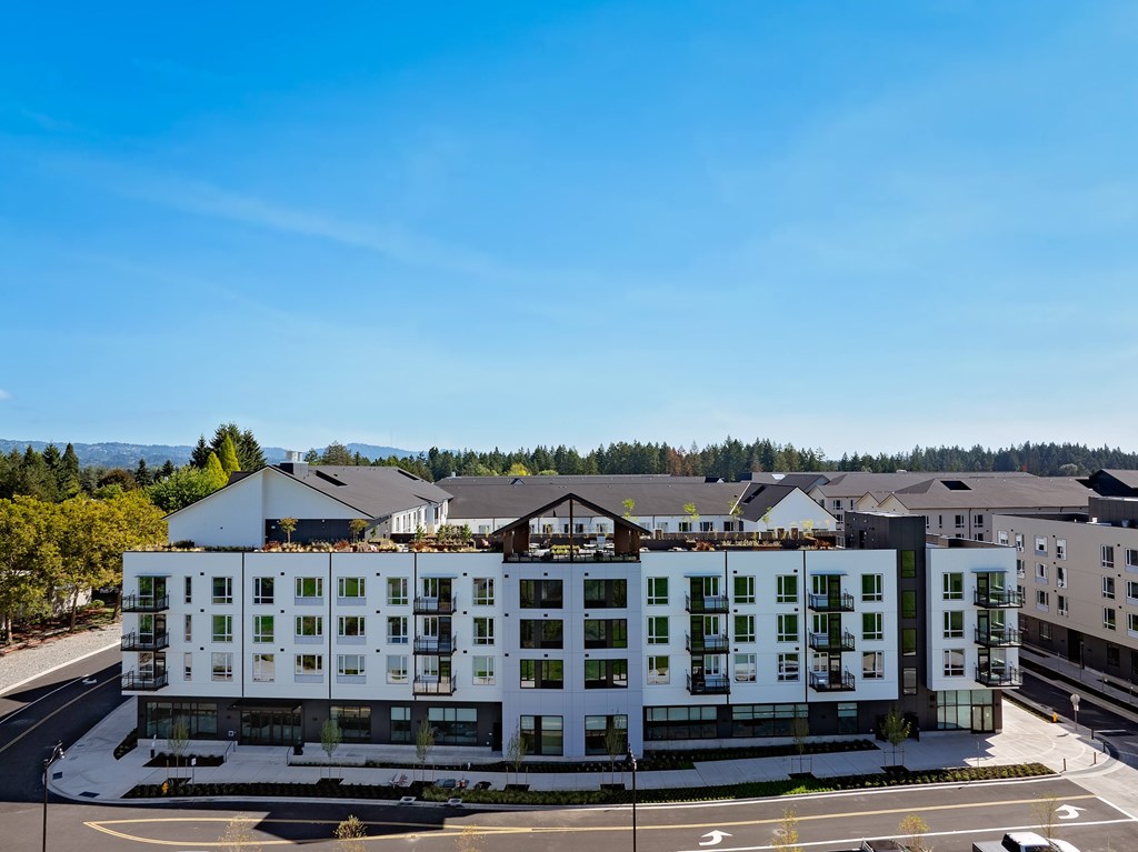 A modern multi-story building with a flat roof and large windows.
