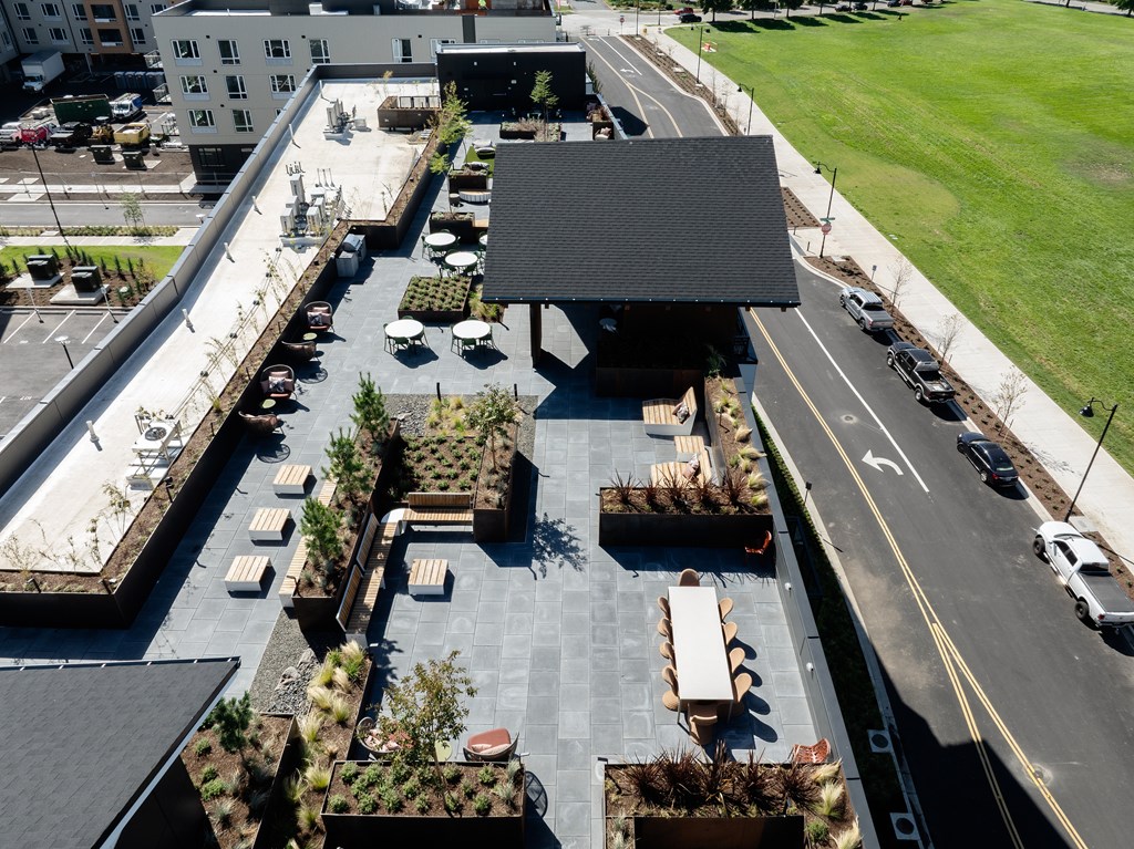 A rooftop patio with a black awning and several tables and chairs.