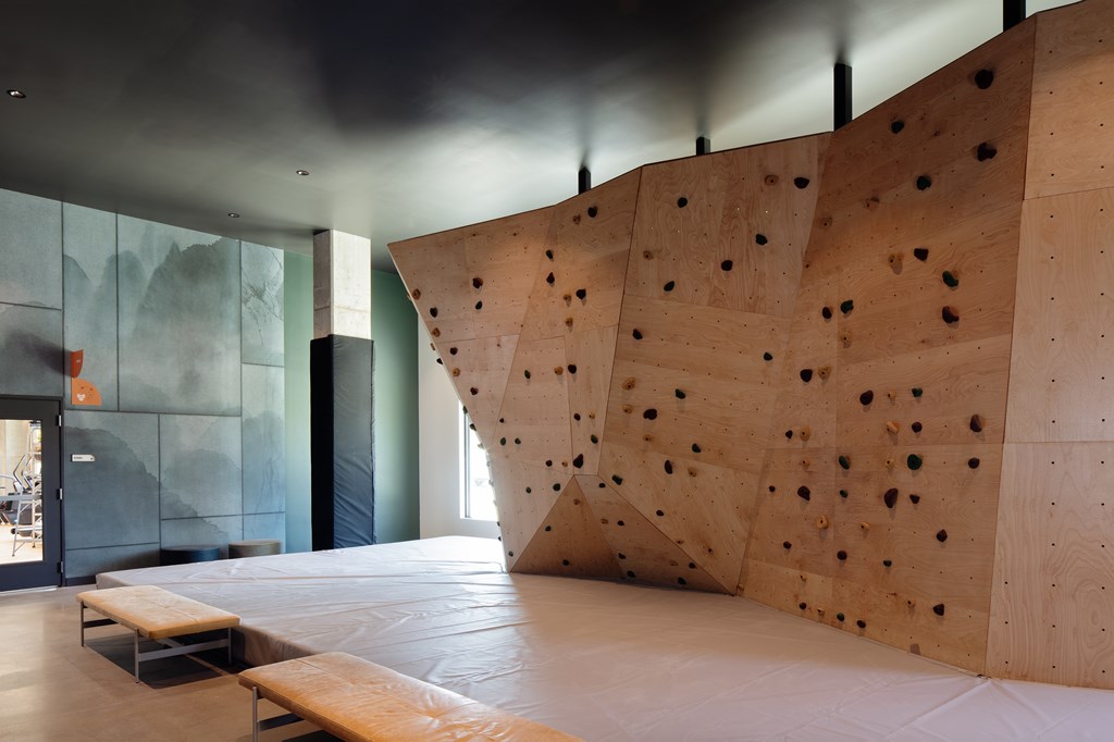 A climbing wall in a gym with wooden planks and holes.
