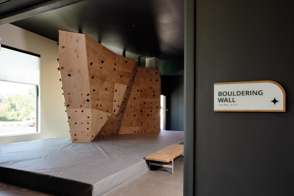 A bouldering wall in a room with a sign that says "BOULDERING WALL".