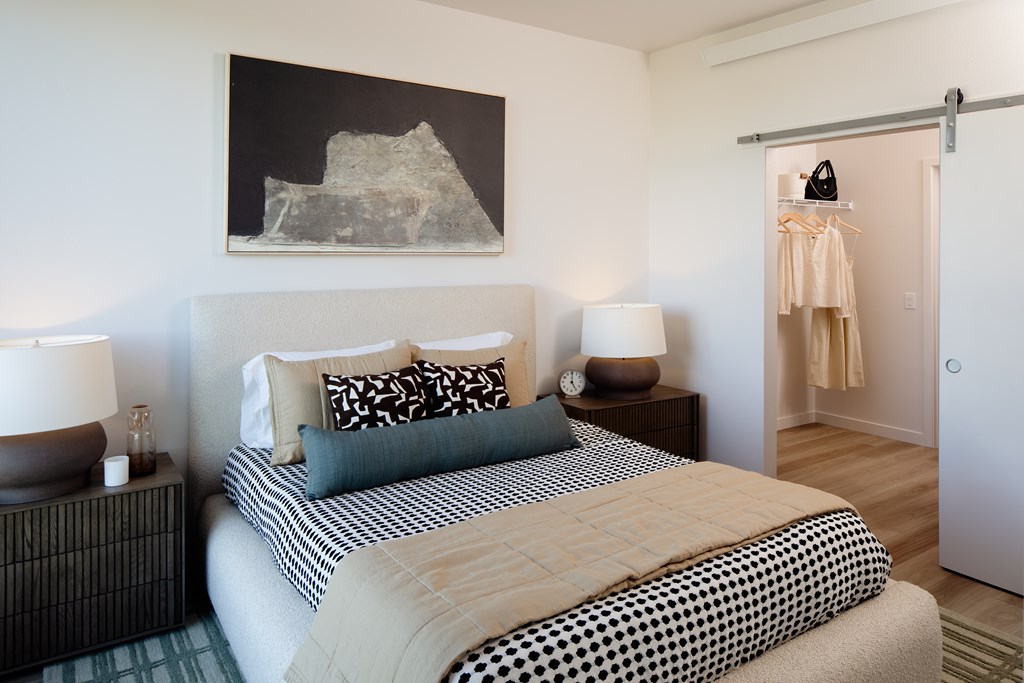 A bedroom with a bed, nightstands, and a painting on the wall.