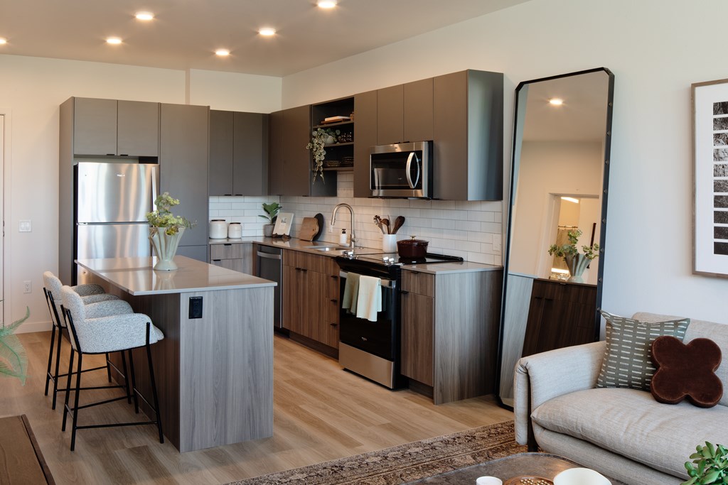 A modern kitchen with a refrigerator, microwave, and oven.