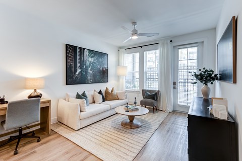 A living room with a white couch, a painting on the wall, and a ceiling fan.