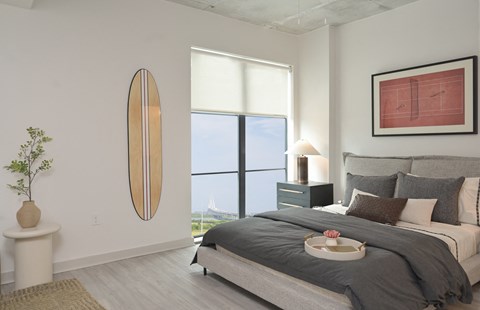 a bedroom with a large window and a bed with pillows