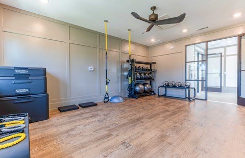 a home gym with hardwood floors and a ceiling fan