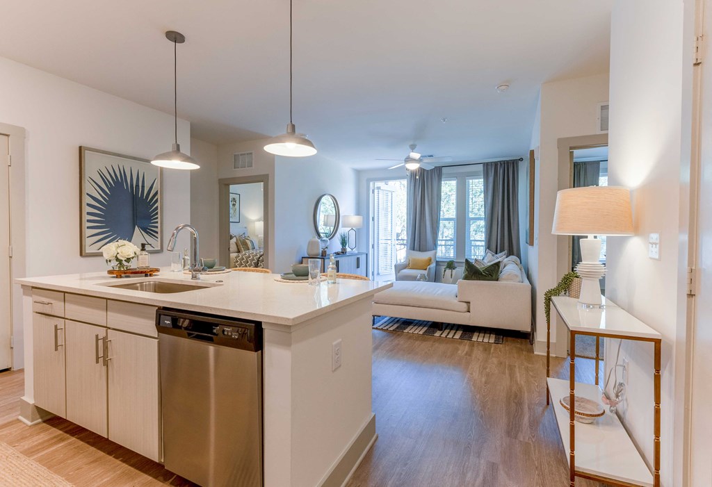 a kitchen with an island and a living room in the background