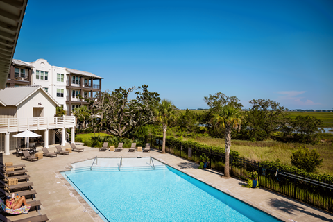 A large swimming pool is surrounded by lounge chairs and umbrellas.