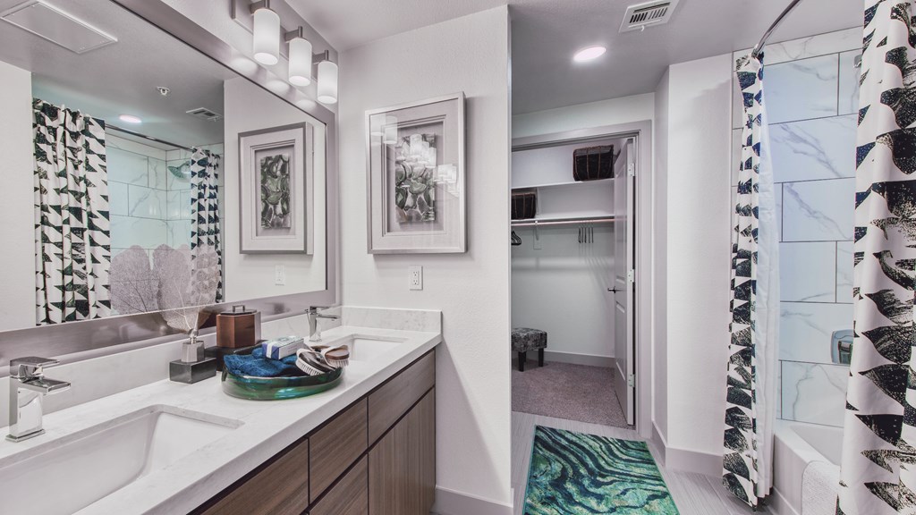 A bathroom with a sink, mirror, and shower.