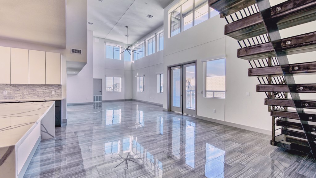 A spacious interior with a marble floor and a staircase on the right.