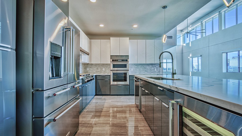 A modern kitchen with stainless steel appliances and wooden flooring.