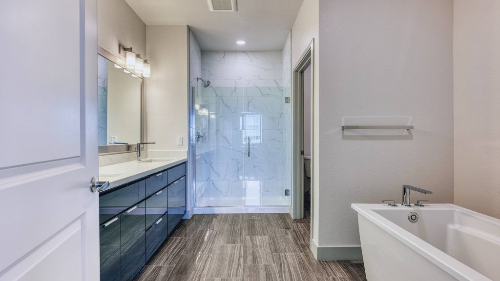 A modern bathroom with a white tub and wooden flooring.
