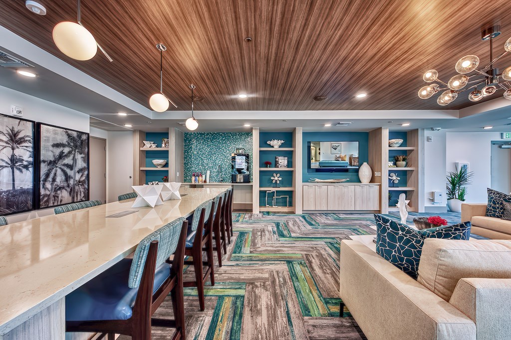 A long wooden table is surrounded by chairs in a room with a wooden ceiling.