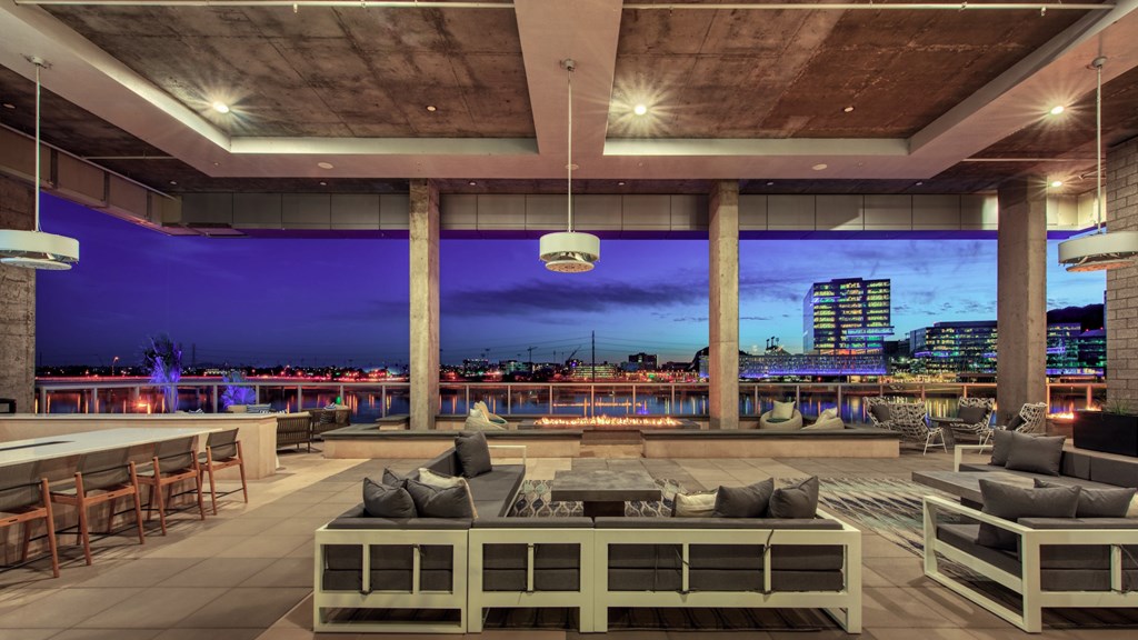 A modern outdoor seating area with a view of the city skyline at dusk.