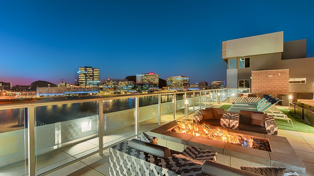 A rooftop patio with a pool and a view of the city at night.