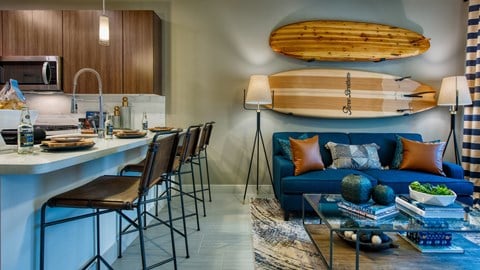 a living room and kitchen with a blue couch and a surfboard on the wall