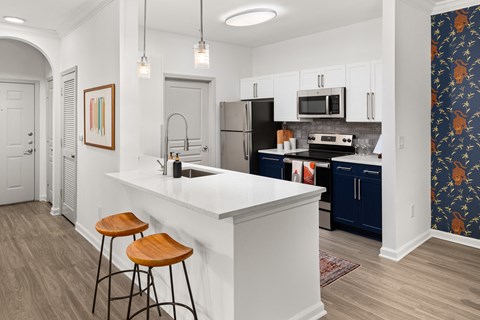 A kitchen with a white counter and bar stools.