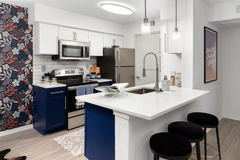 A kitchen with a white counter top and blue cabinets.