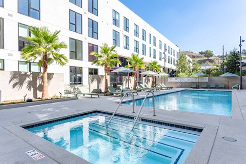 A pool in front of a building with palm trees.