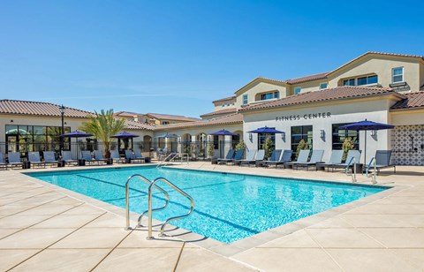 A swimming pool is surrounded by sun loungers and umbrellas.
