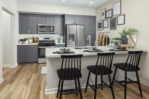 A kitchen with a white counter top and black bar stools.