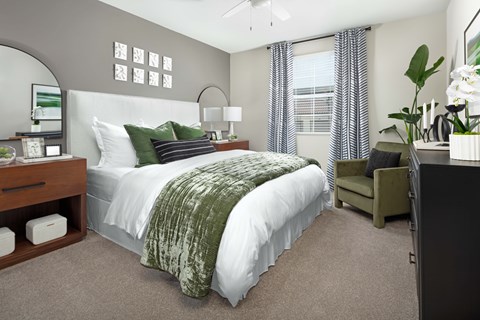 A bedroom with a large bed and a green chair.