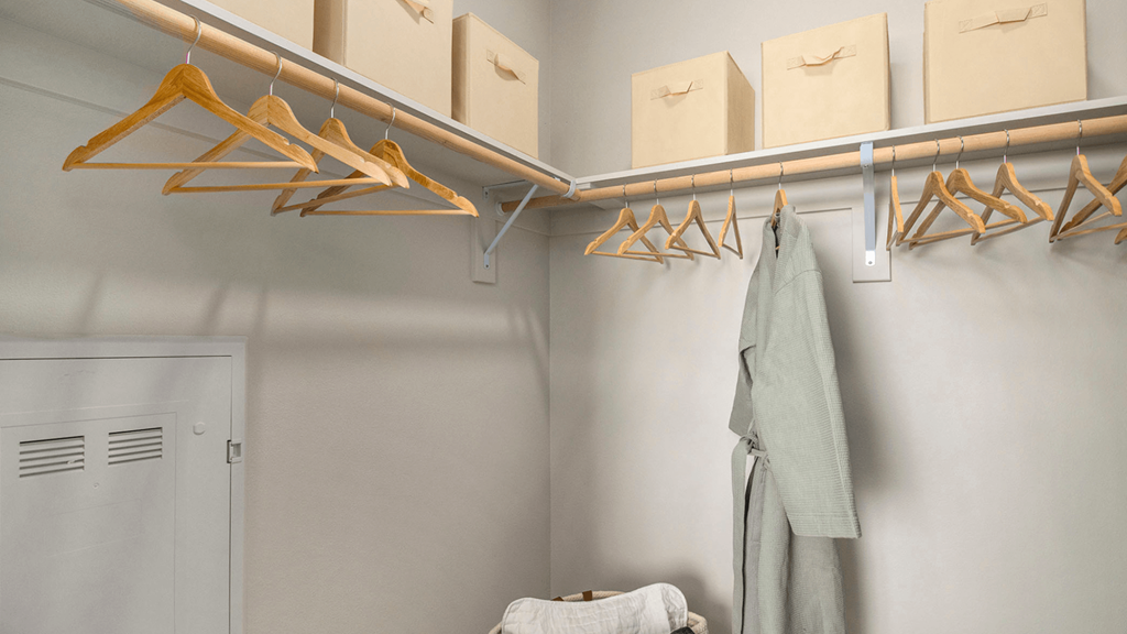 a walk in closet with wooden clothes hangers and a closet door