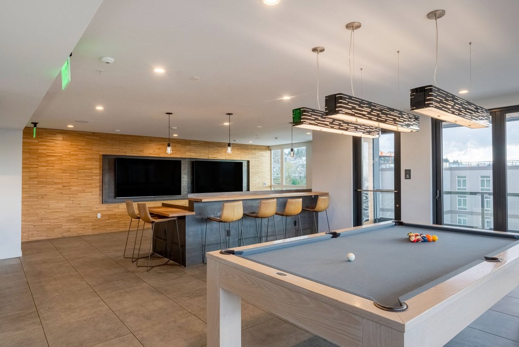 A billiard table is in the middle of a room with a brick wall and a television.at Axle, Seattle, WA 98119